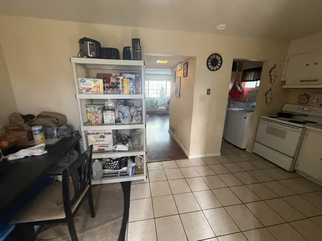 Kitchen featuring white electric stove, white cabinets, extractor fan, and light countertops