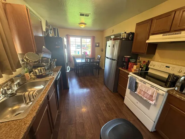 Kitchen with stainless steel appliances, a textured ceiling, wood finish cabinetry, and dark wood-style floors
