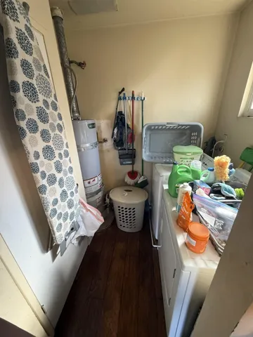 Laundry area featuring dark wood-style flooring, independent washer and dryer, and strapped water heater
