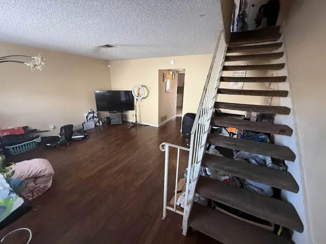 Staircase featuring a textured ceiling and wood finished floors