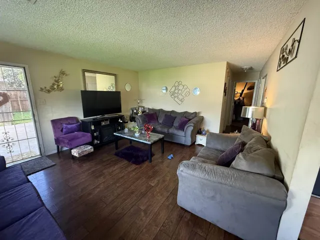 Living area featuring dark wood finished floors and a textured ceiling