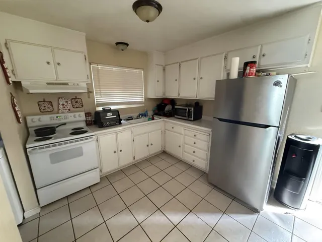 Kitchen with stainless steel appliances, white cabinets, light countertops, and light tile patterned floors