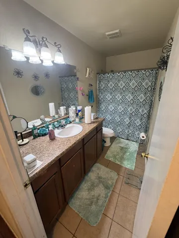 Full bathroom with vanity, a shower with shower curtain, and light tile patterned floors
