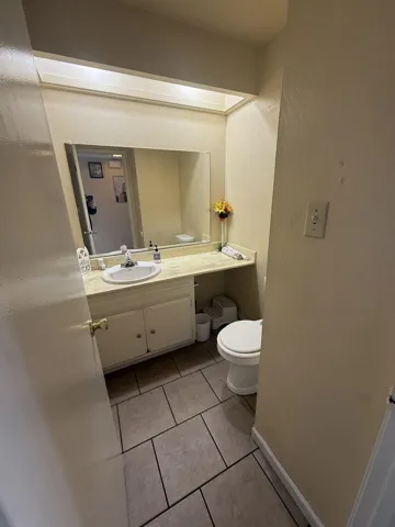 Half bathroom featuring vanity, a textured wall, and light tile patterned flooring