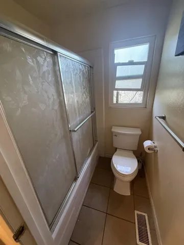 Bathroom with shower / bath combination with glass door and light tile patterned flooring