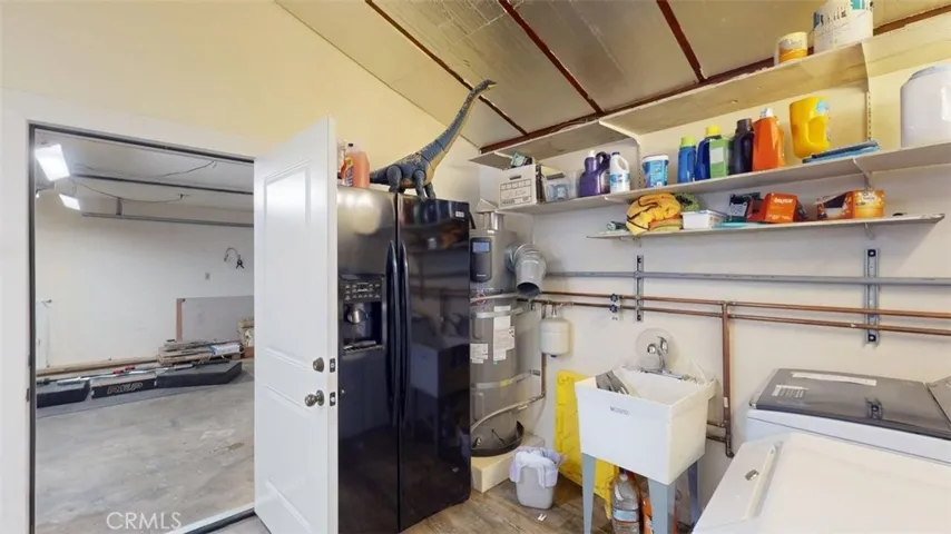 Laundry room with refrig, water heater and wash basen looking into garage.