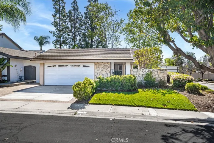 Charming single-story home with stone accents, a two-car garage, and a beautifully maintained front yard.