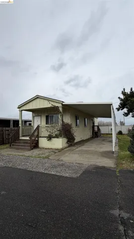 Manufactured / mobile home with an attached carport, concrete driveway, and board and batten siding