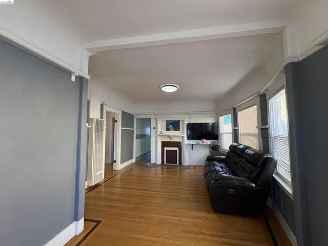 Living room with wood finished floors, a fireplace with flush hearth, and a heating unit