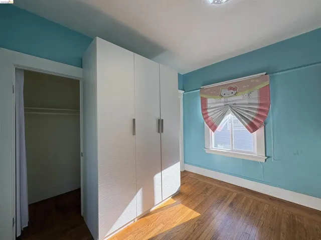 Unfurnished bedroom with dark wood-style flooring and baseboards