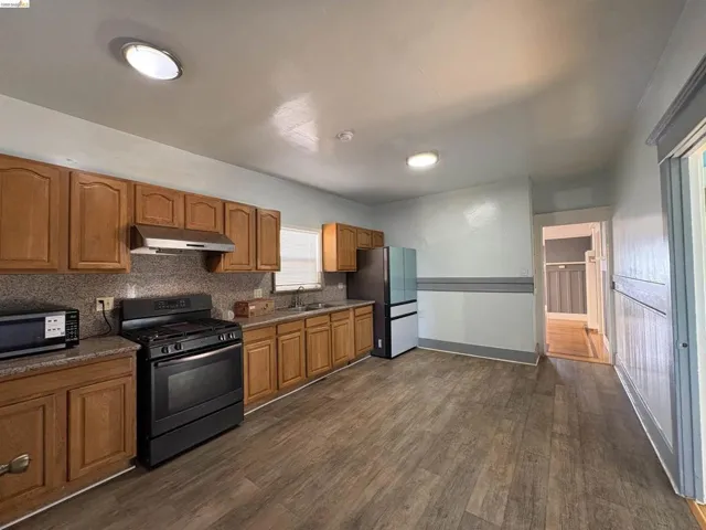 Kitchen with stainless steel appliances, wood finish cabinetry, dark wood finished floors, and tasteful backsplash