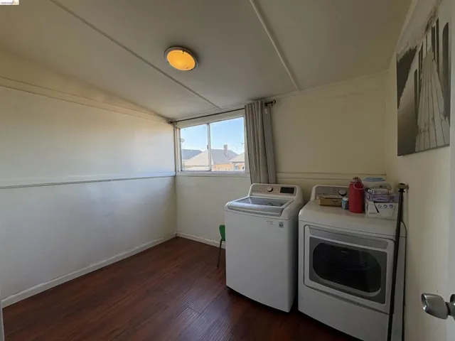 Laundry area with vaulted ceiling, dark wood-style flooring, and independent washer and dryer