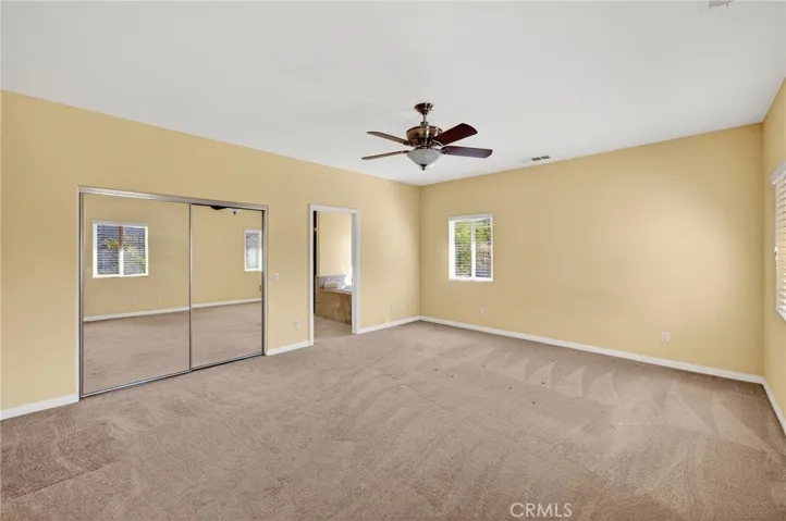 The primary suite offers generous floor space, carpet, mirrored closet doors  and multiple windows that invite in the natural light.
