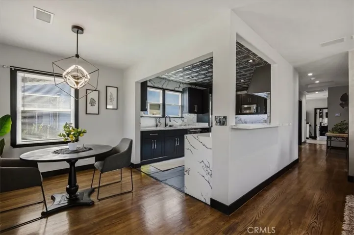 Wood flooring, modern lighting in dining room open to large custom chef's kitchen