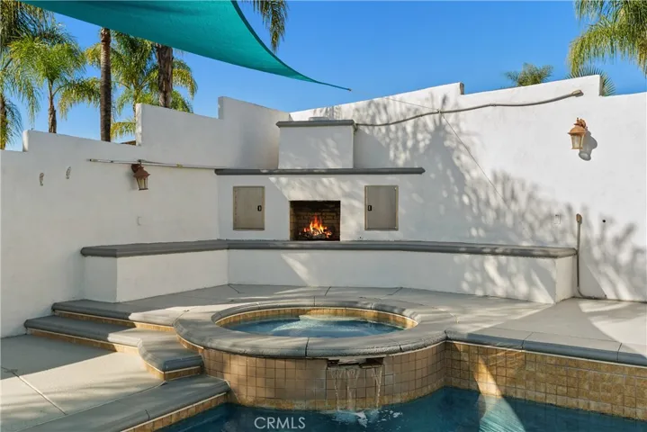 Resort-style pool and spa with fireplace backdrop, perfect for relaxing or entertaining