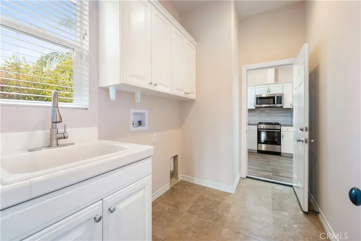 Laundry room with cabinets & a built-in sink. Entrance to ADU from inside the house. There is 2nd entrance from the side yard area.