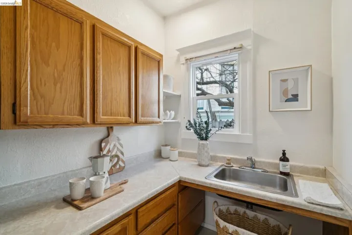 Kitchen featuring wood finish cabinetry, a textured wall, open shelves, and light countertops