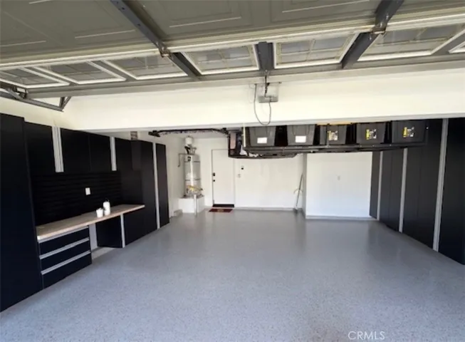 Finished garage with epoxy flooring, extensive cabinetry, workspace, and overhead storage