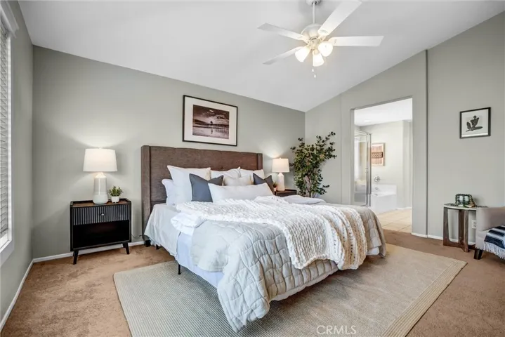 Expansive primary suite with vaulted ceilings, ceiling fan, and abundant natural light