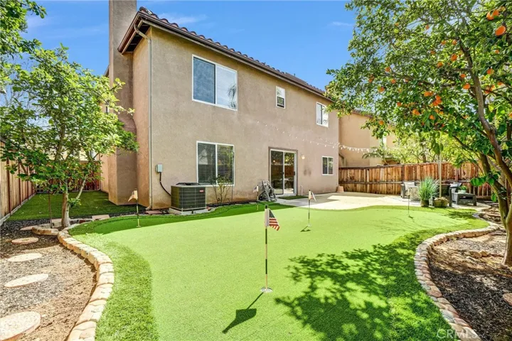 Large backyard with custom putting green, curved landscape borders, and adjacent entertaining patio