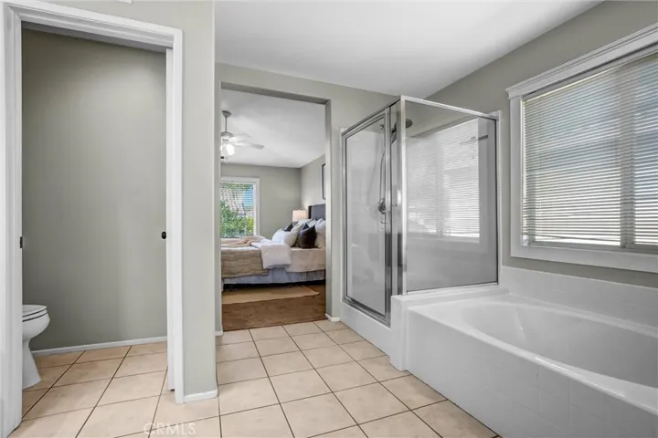 Primary bath with soaking tub, separate glass-enclosed shower, and natural light