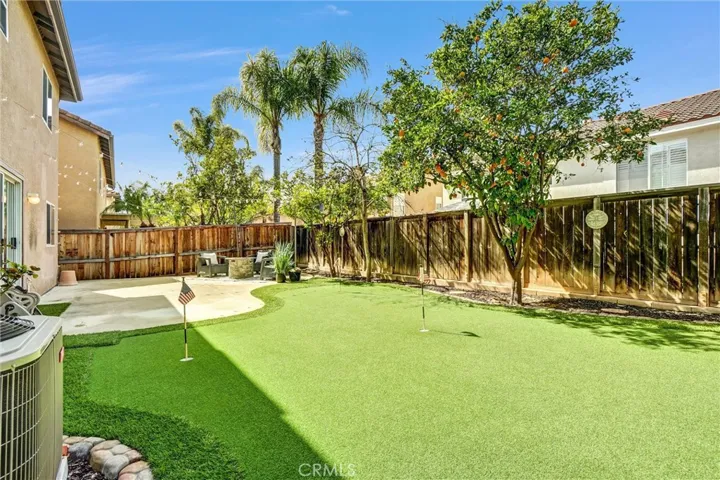 Low-maintenance backyard with artificial turf putting green and mature landscaping