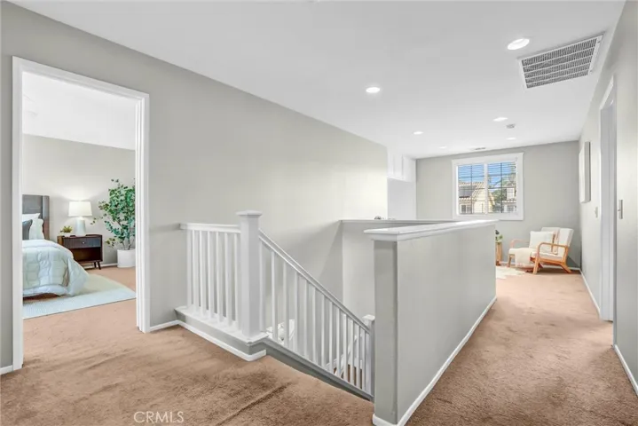Upstairs hallway connecting bedrooms and loft area with recessed lighting and neutral finishes