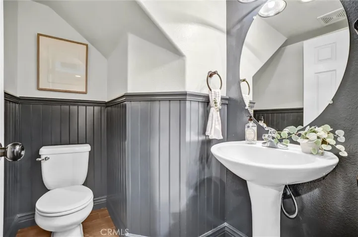 Stylish main-level powder room featuring beadboard wainscoting, pedestal sink, and modern lighting