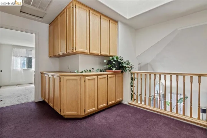 Bar area with light wood finish cabinetry, dark colored carpet, and light countertops