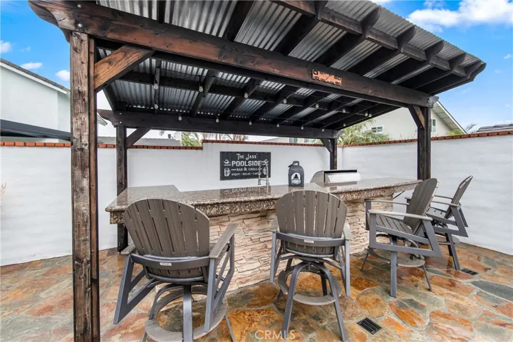 Luxurious backyard retreat featuring a custom pool, spa, and expansive covered outdoor kitchen.