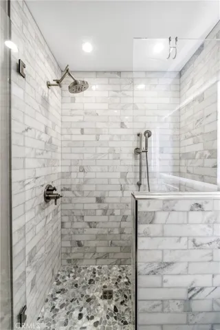 Bright designer bath with marble shower, dual heads, stacked stone accents, and elegant vanity.
