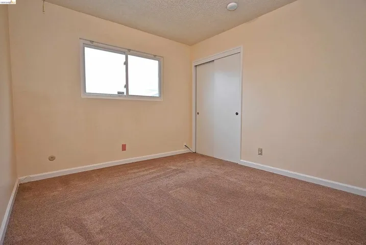 Unfurnished bedroom with carpet floors, a textured ceiling, and a closet
