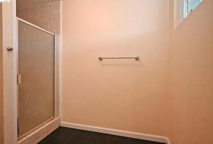 Full bath featuring a shower stall and dark tile patterned flooring