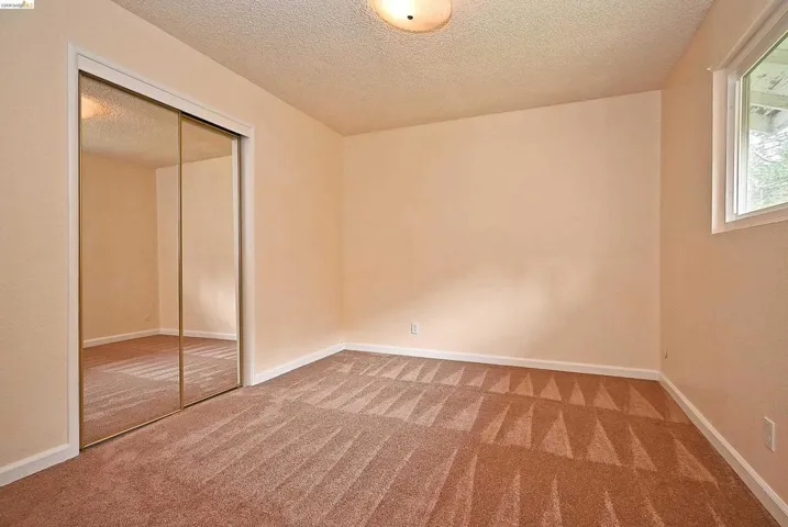 Unfurnished bedroom featuring a closet, a textured ceiling, and carpet flooring