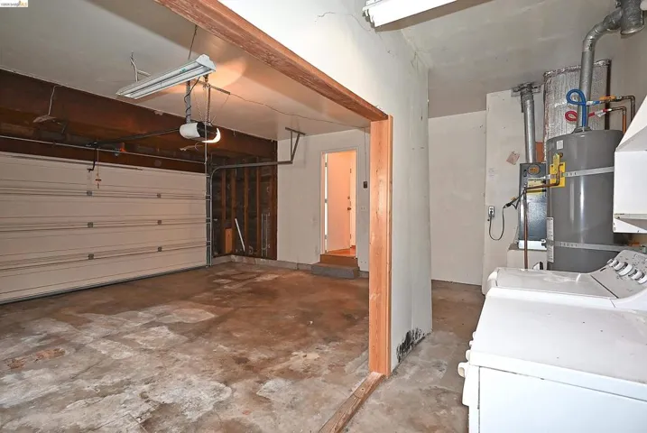 Garage featuring secured water heater, a garage door opener, and separate washer and dryer