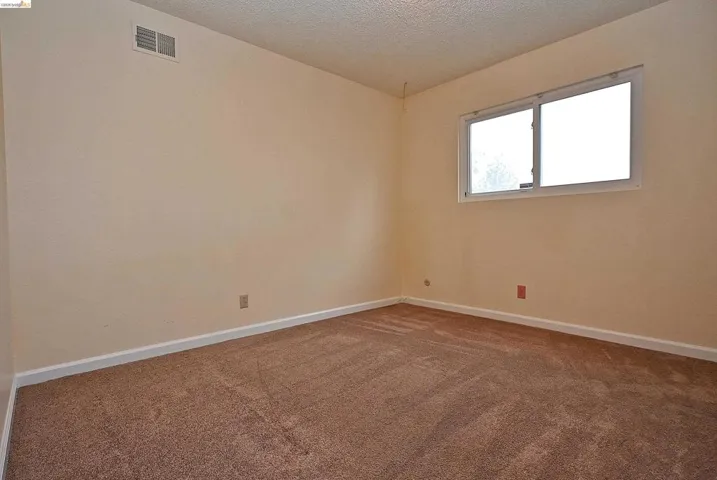 Carpeted empty room featuring baseboards and a textured ceiling