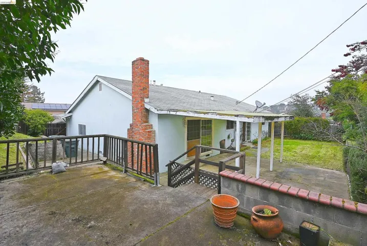 Back of house with stucco siding, a patio area, a chimney, and a shingled roof