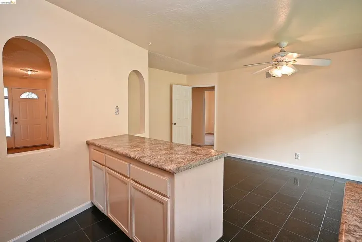 Kitchen with arched walkways, a ceiling fan, light countertops, a peninsula, and light wood finish cabinetry