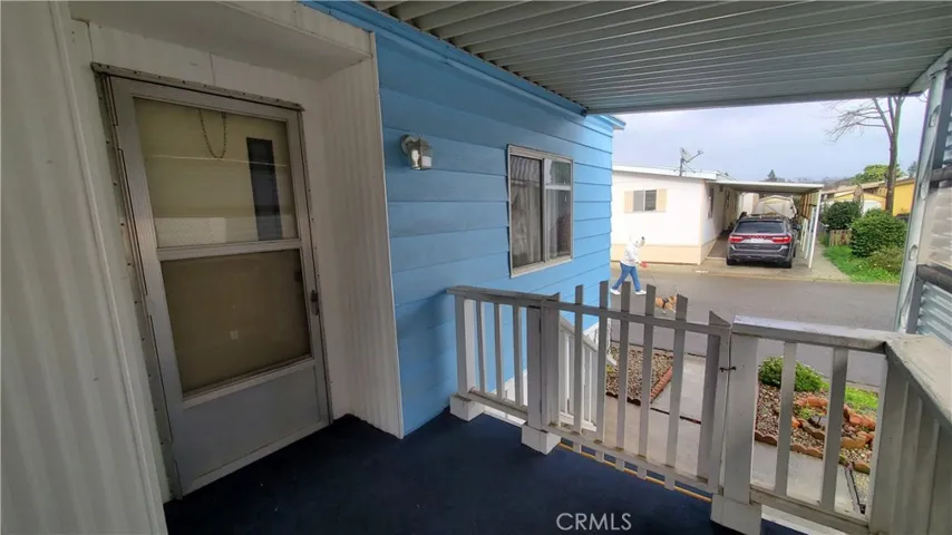 View of front door and covered front porch area with railing and swing gate at stairs.