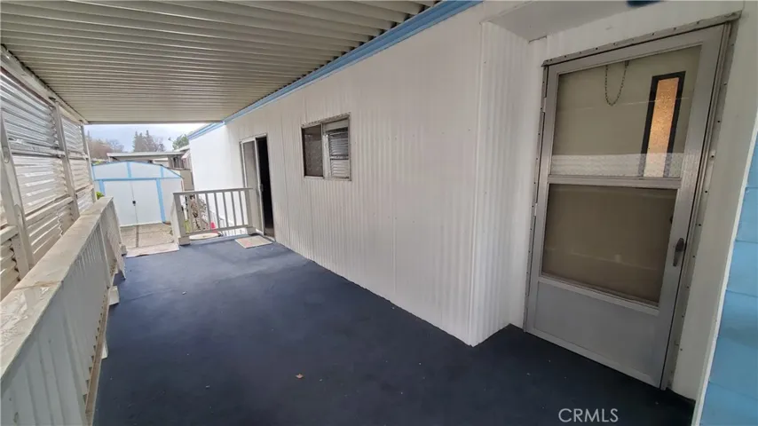 View of covered porch area with front door entry on the right & slider further down enters into the family room/kitchen area.