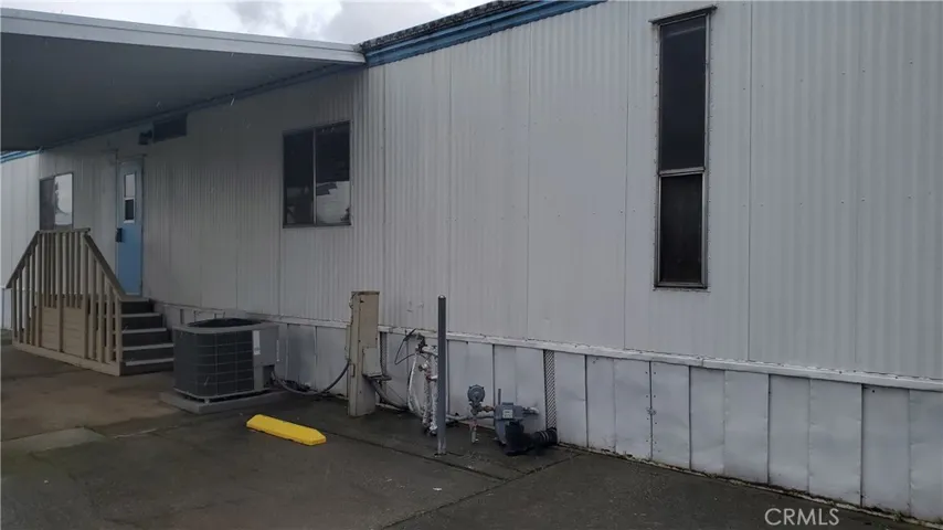View of carport area with steps leading to laundry room entry.