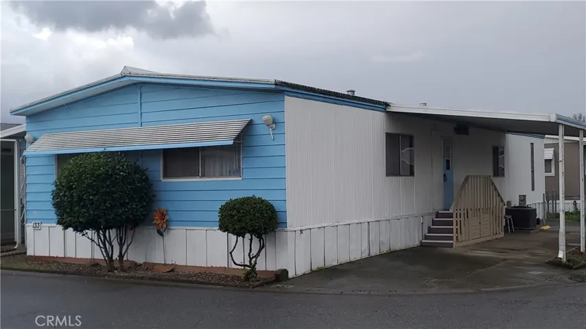 View of front with carport on right and steps to entry into the laundry room.