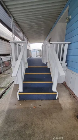 View of front steps with hand rails and swing gate leading to covered front porch.