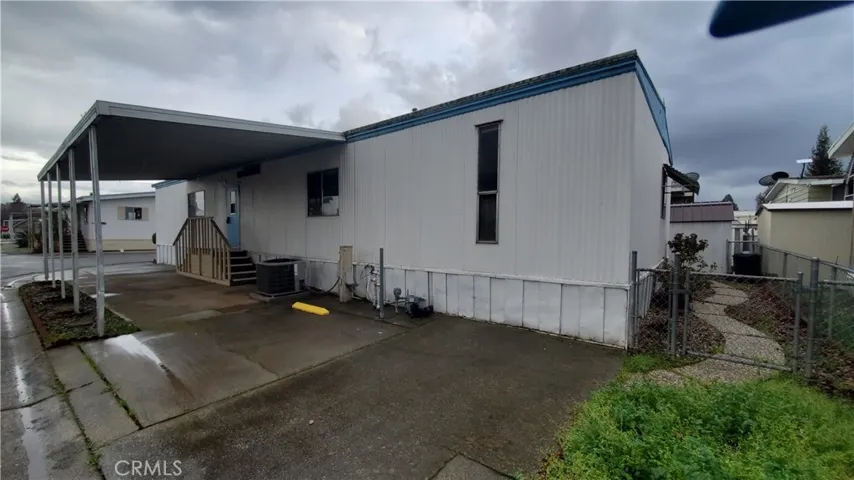 View of back and carport area with steps leading to laundry room entry.