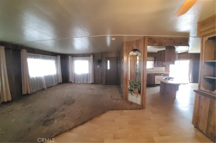 View of living room area with front door entry, kitchen with cook island to the right.