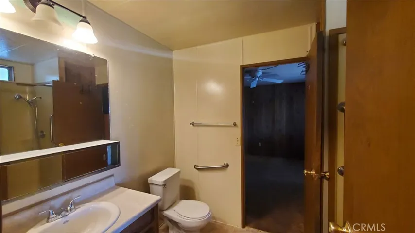 View of guest bathroom with walk in shower, door leading to laundry room and door leading to guest bedroom.
