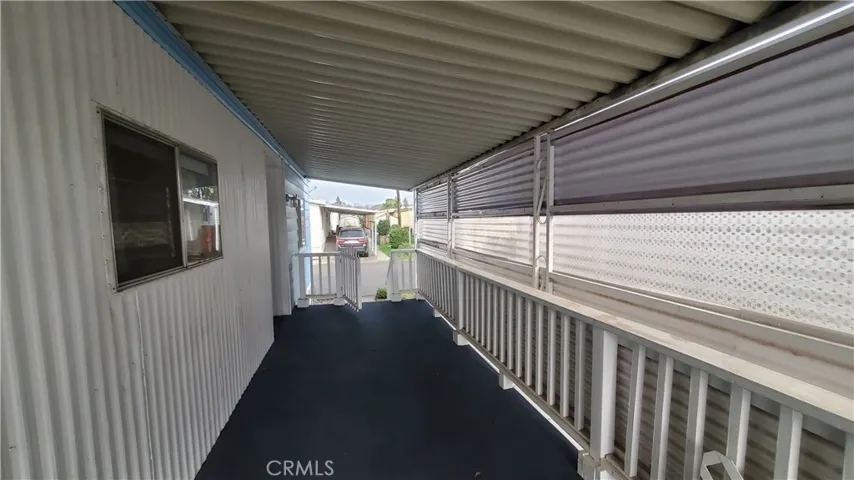 View of covered front porch with railing and swing gate leading to entry steps.