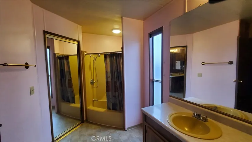 View of master bathroom with tub/shower and walk in closet with mirrored door.