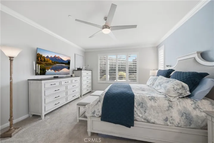 Primary bedroom with shutters and ceiling fan.