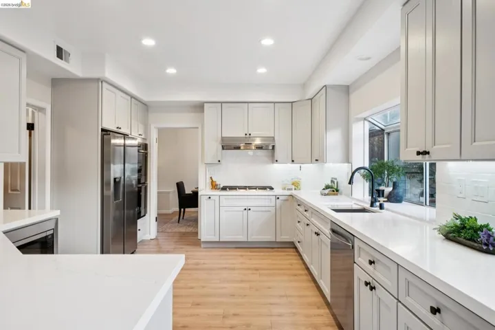 Kitchen featuring light wood finished floors, decorative backsplash, recessed lighting, light stone countertops, and stainless steel appliances